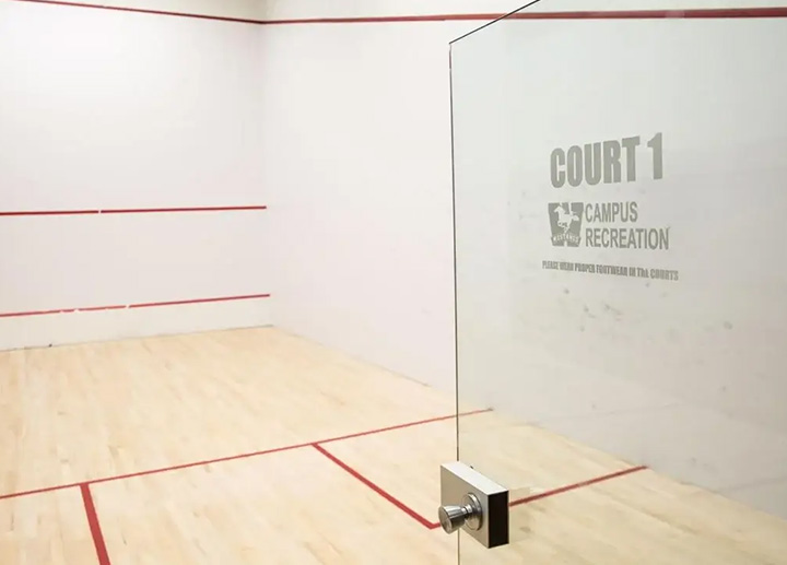 A transparent door with the mustang logo opening to a squash court