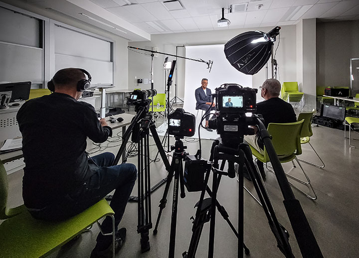 A scene that is being recorded where you see the cameraman and an interviewer