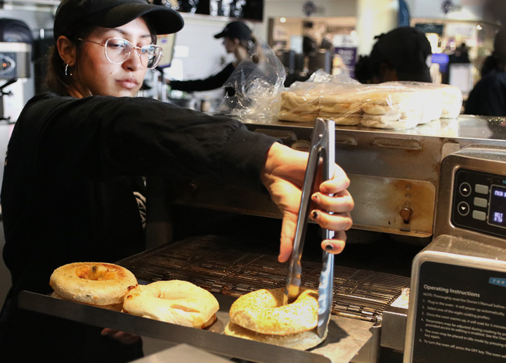 A female worker grabbing bagels in a kitchen at the Spoke